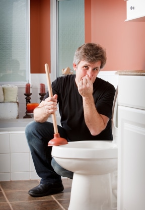 Man plunging toilet and holding his nose.