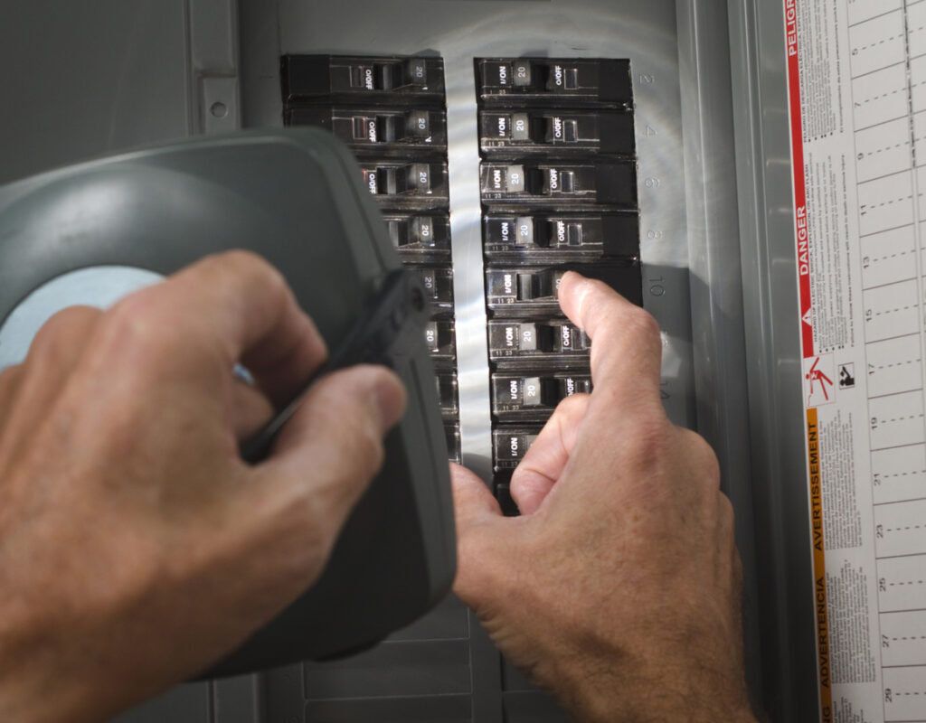 Man holding flashlight on circuit breaker