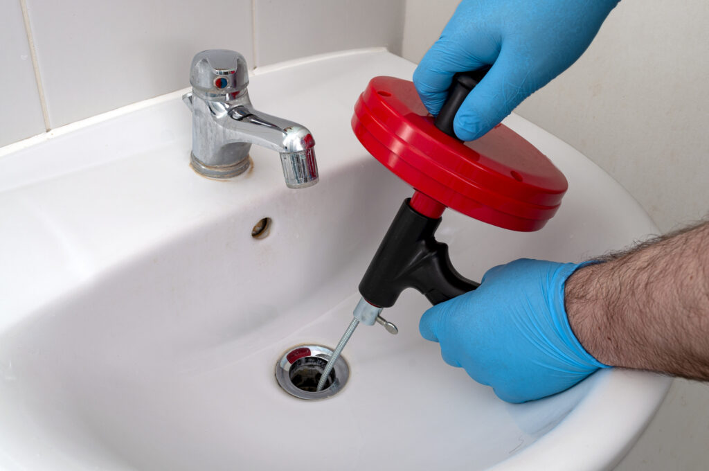 Drain snake tool being used for plumbing maintenance by Penguin Air, Plumbing & Electrical