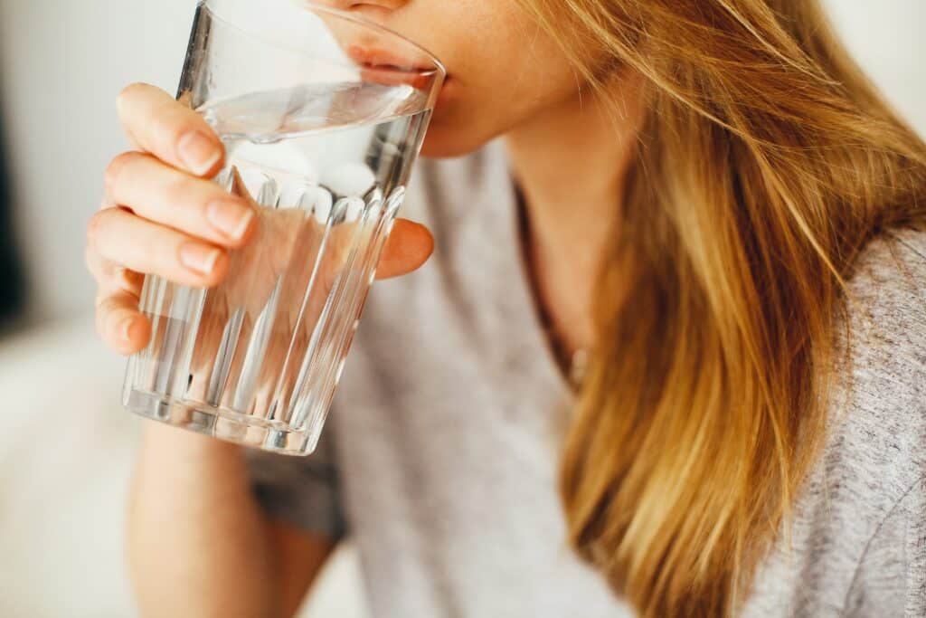 Woman drinking water from a glass, highlighting the importance of clean water systems