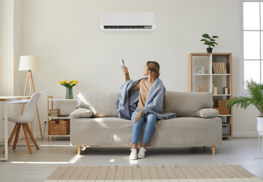 A woman sitting on a couch using a remote to control her zoned HVAC system.