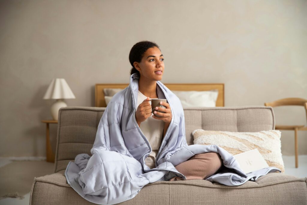 Woman sitting on a couch with a blanket and a mug.